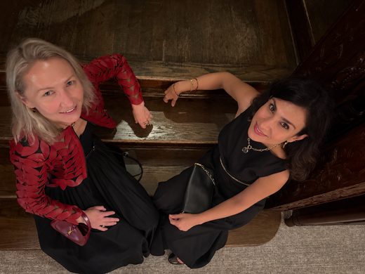 The two of us sitting on a staircase in long black dresses, seen from above.
